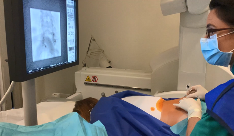 Photo d'un médecin radiologue à Genève en train de réaliser une infiltration thérapeutique lombaire sous contrôle radiographique