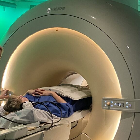 Photo d'une technicienne en imagerie médicale en train de préparer une patiente à passer une IRM abdominale dans le cadre de douleurs au ventre