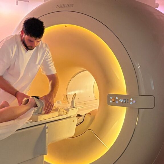 Photo d'un technicien en imagerie médicale en train de préparer un patient à passer une IRM pour suspicion de tumeur osseuse